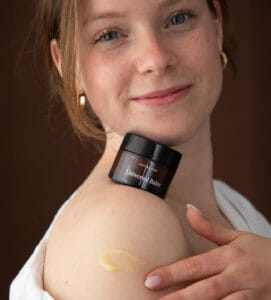 a woman holding a jar of cream on her shoulder