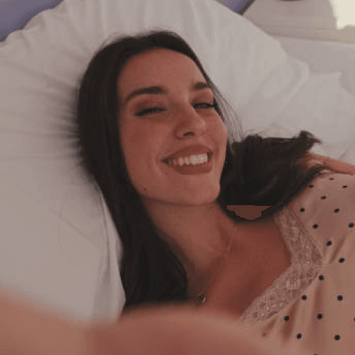 a woman lying on a bed taking a selfie