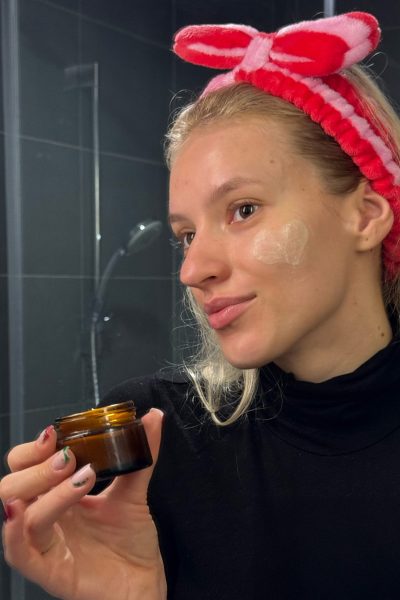 a woman wearing a headband holding a jar of cream